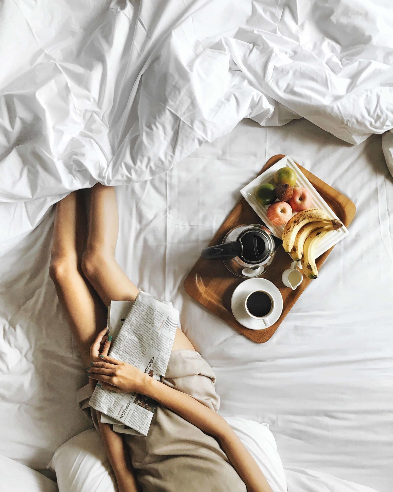 Woman enjoying coffee and fruit while resting in bed