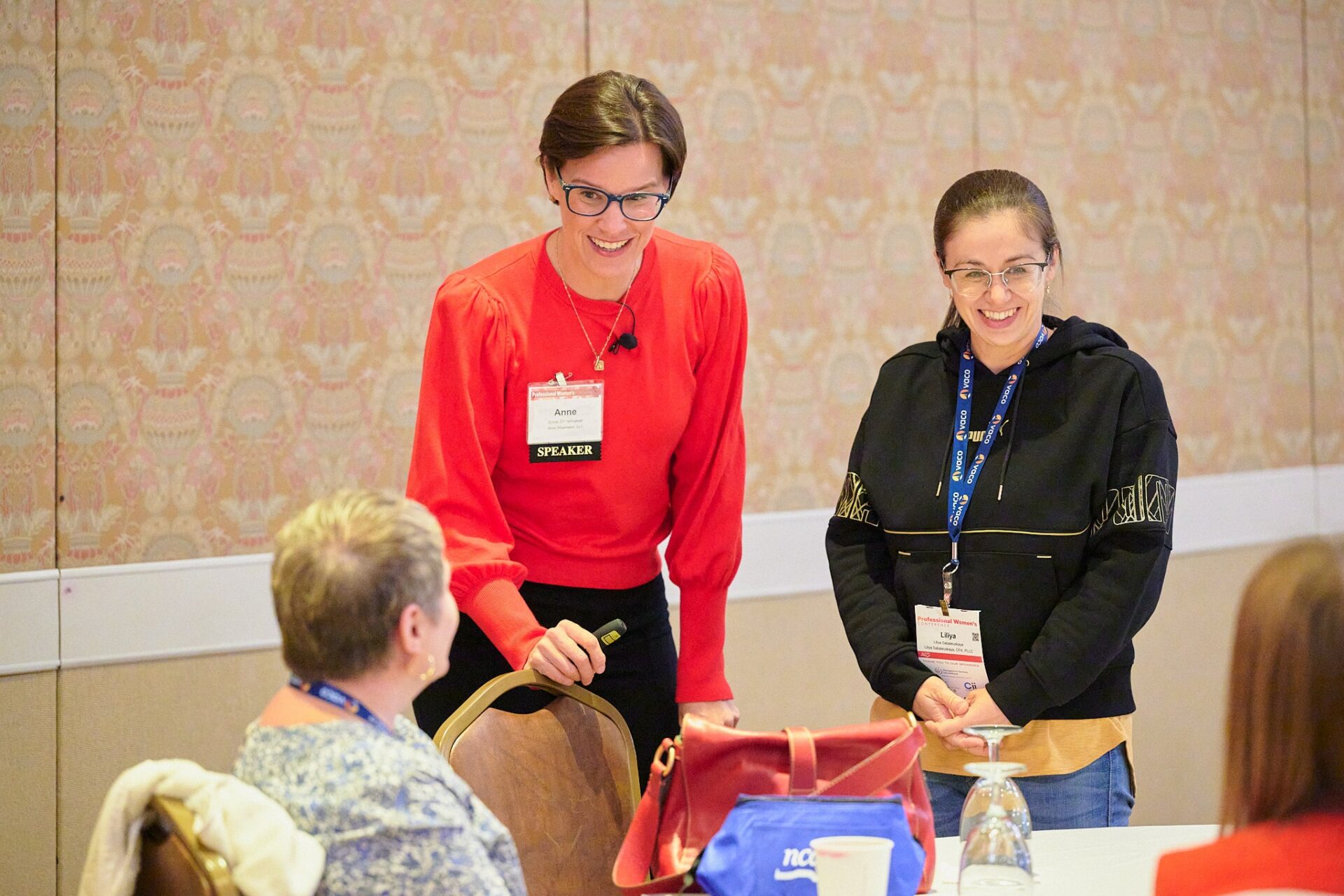 Anne Shoemaker in a red sweater participating in an interactive workshop activity.